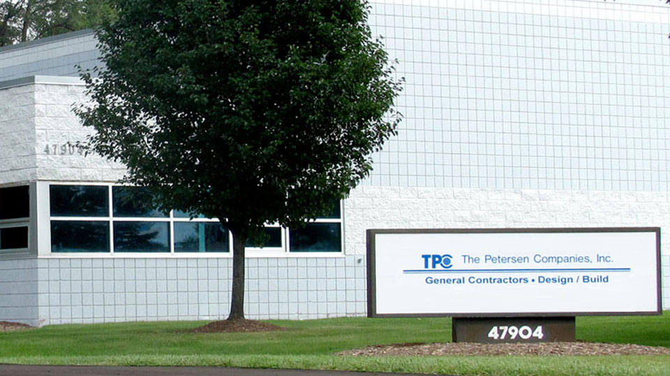 External view of the Petersen Companies with white and gray sign out front with business name and address. 