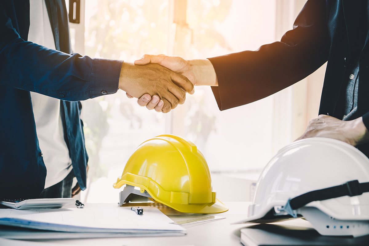 Successful deal, male architect shaking hands with client in construction site after confirm blueprint for building services.
